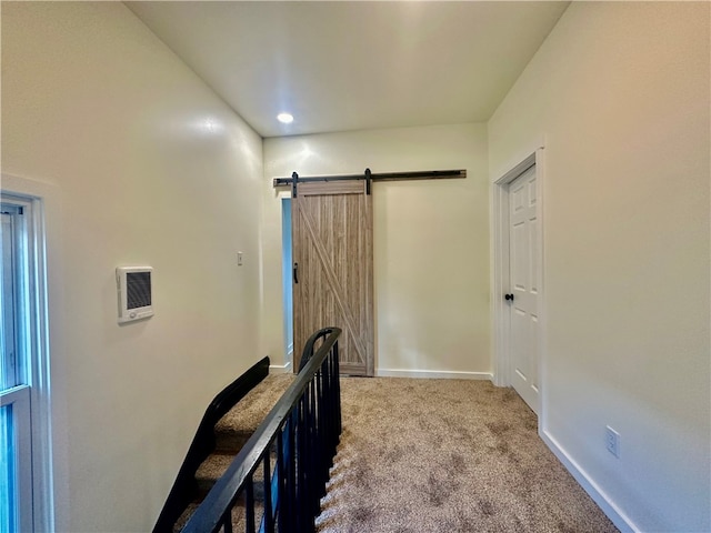 corridor featuring a barn door and light carpet