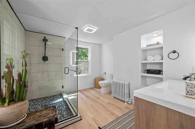 bathroom with toilet, radiator, built in shelves, wood-type flooring, and vanity