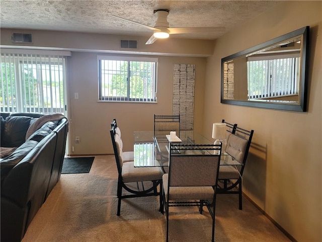 dining space featuring carpet floors, a textured ceiling, and ceiling fan