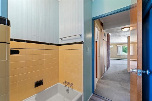 bathroom featuring a washtub, tile walls, crown molding, and a baseboard radiator