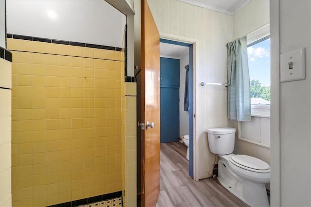 bathroom featuring toilet, a tile shower, ornamental molding, and hardwood / wood-style floors