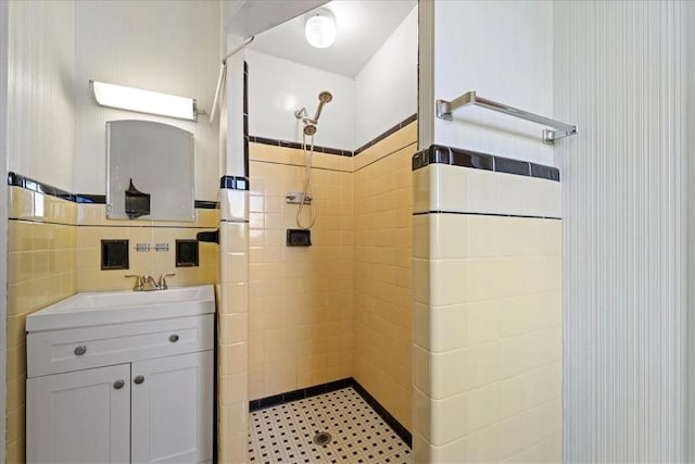 bathroom featuring tile walls, tiled shower, and vanity