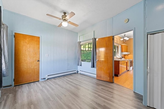 spare room with light wood-type flooring, sink, and a baseboard radiator