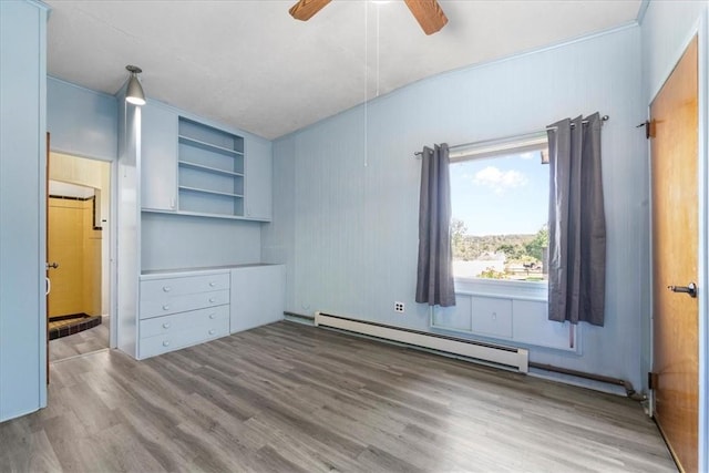 unfurnished bedroom featuring ceiling fan, baseboard heating, and hardwood / wood-style flooring