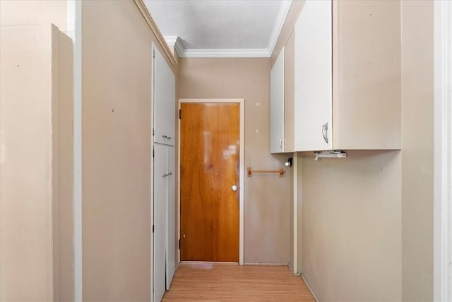 corridor with light hardwood / wood-style floors and ornamental molding