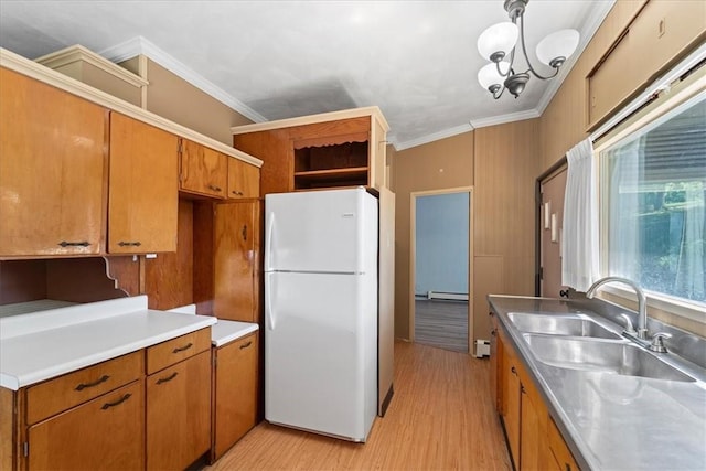 kitchen with decorative light fixtures, sink, light wood-type flooring, ornamental molding, and white refrigerator