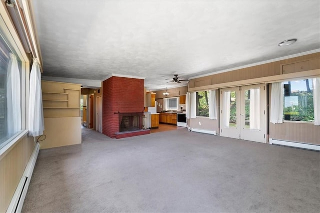 unfurnished living room featuring light colored carpet, a baseboard heating unit, a fireplace, and crown molding