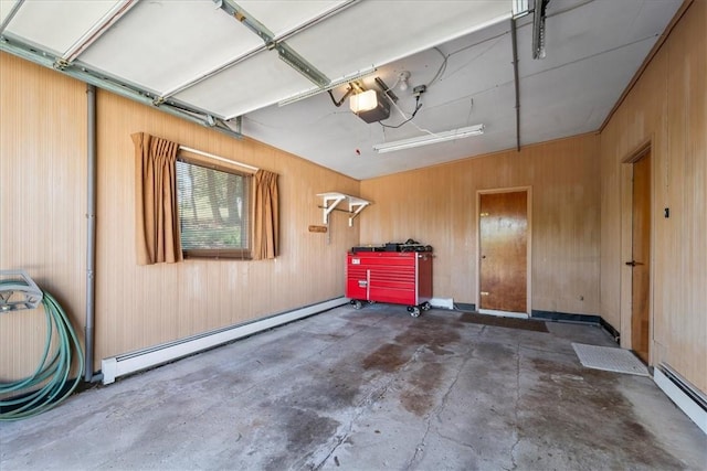 garage featuring a baseboard radiator, wood walls, and a garage door opener