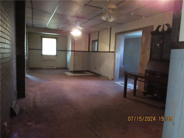 basement featuring carpet, ceiling fan, baseboard heating, and a paneled ceiling