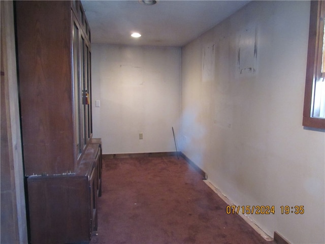 hall with dark colored carpet