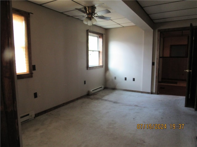 carpeted spare room featuring a drop ceiling, a baseboard heating unit, and ceiling fan