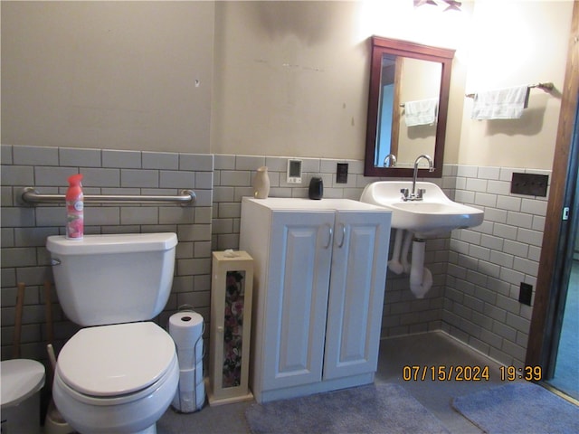 bathroom with sink, tile walls, and toilet