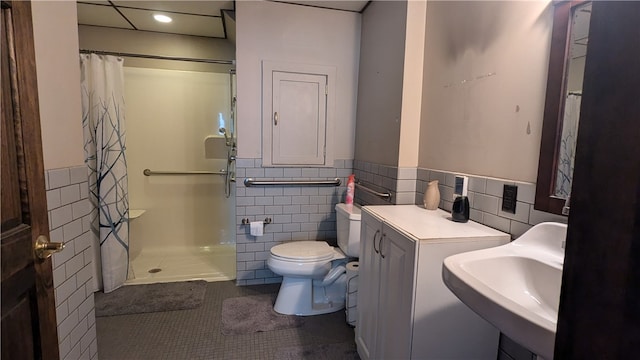 bathroom featuring toilet, sink, a shower with curtain, tile walls, and tile patterned flooring