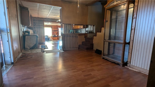 unfurnished room featuring wooden walls, dark hardwood / wood-style floors, and a paneled ceiling