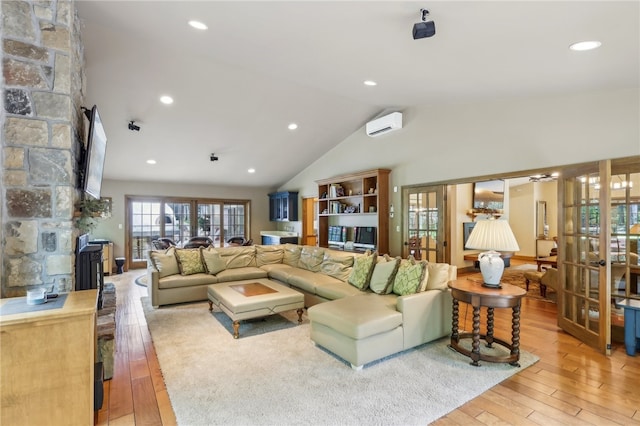 living room with an AC wall unit, french doors, light hardwood / wood-style flooring, and lofted ceiling