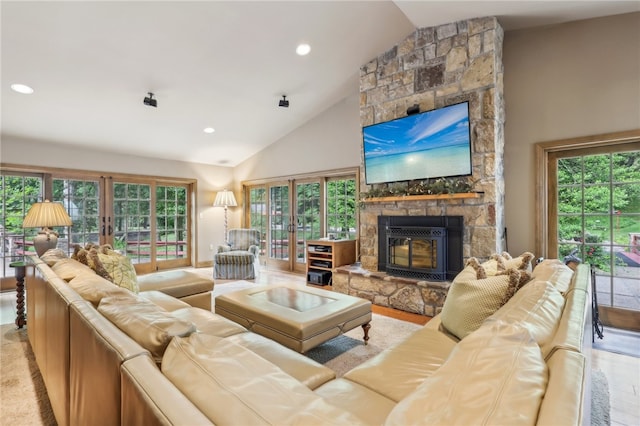 living room with a healthy amount of sunlight, a stone fireplace, and high vaulted ceiling