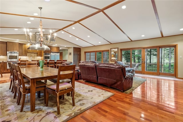 dining room featuring light hardwood / wood-style floors, vaulted ceiling, and an inviting chandelier