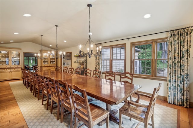 dining room with vaulted ceiling, a notable chandelier, and light hardwood / wood-style floors