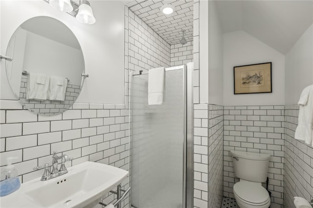 bathroom with tile walls, toilet, vaulted ceiling, and a shower with door