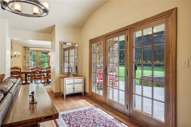 entryway featuring a notable chandelier, wood-type flooring, french doors, and vaulted ceiling