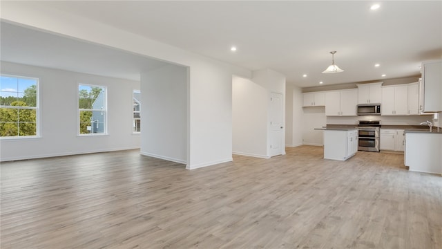 kitchen featuring light hardwood / wood-style floors, white cabinetry, a kitchen island, stainless steel appliances, and decorative light fixtures