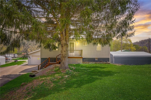 view of front of home featuring a garage, a lawn, and an outbuilding