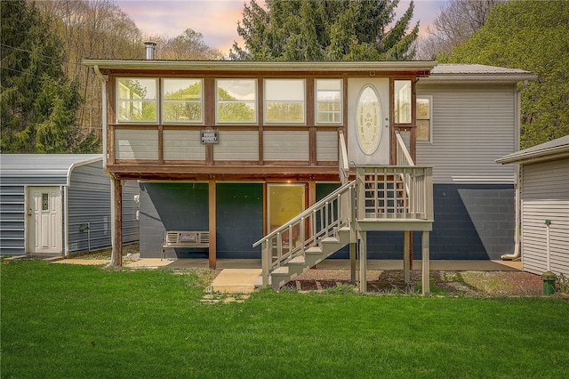 back house at dusk featuring a lawn