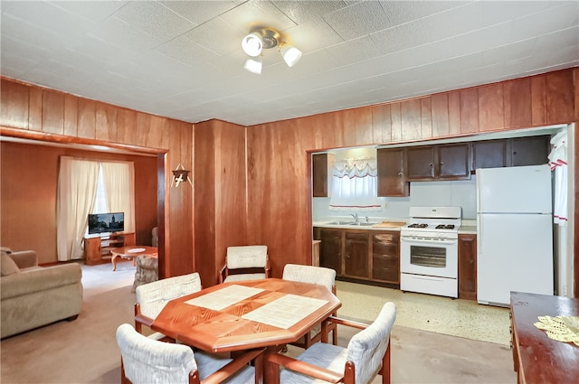 kitchen with sink, wooden walls, and white appliances