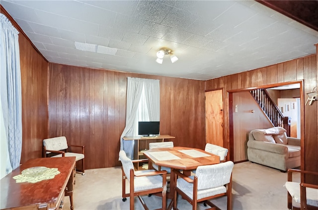 carpeted dining area featuring wooden walls