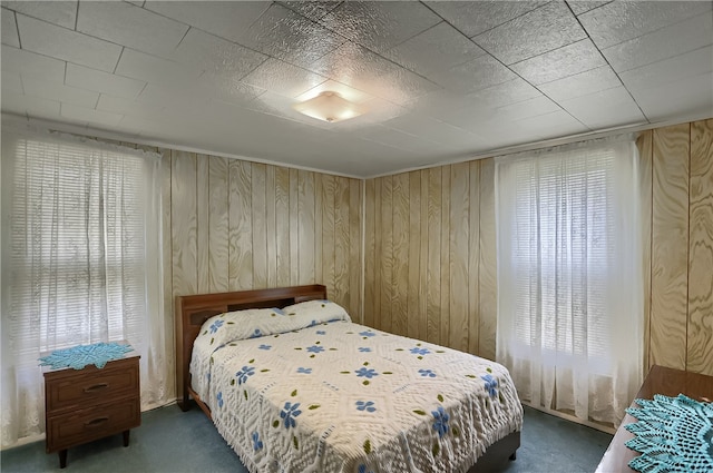 carpeted bedroom featuring wood walls