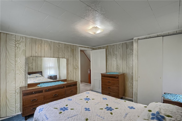 bedroom featuring a closet, carpet floors, and wood walls