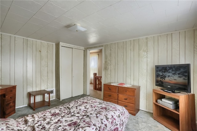 carpeted bedroom with a closet and wooden walls