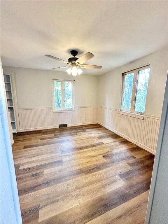 empty room featuring ceiling fan, a wealth of natural light, and light hardwood / wood-style flooring