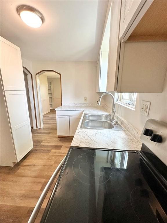 kitchen featuring white cabinetry, stainless steel electric stove, light hardwood / wood-style flooring, and sink