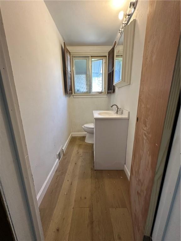 bathroom featuring hardwood / wood-style flooring, toilet, and vanity