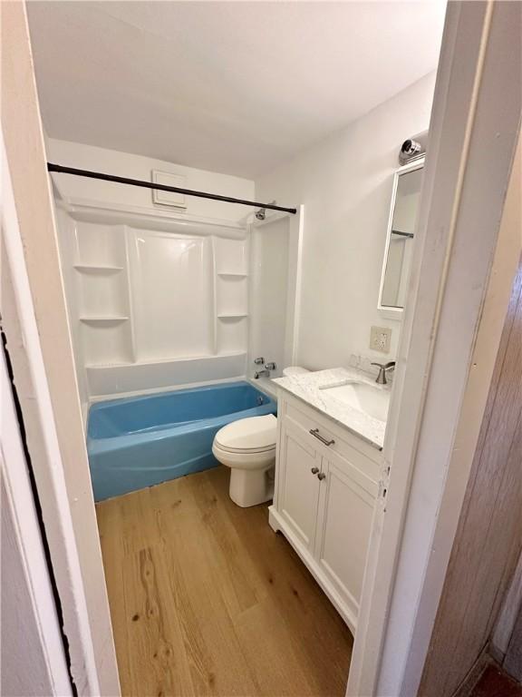 full bathroom with washtub / shower combination, toilet, wood-type flooring, and vanity