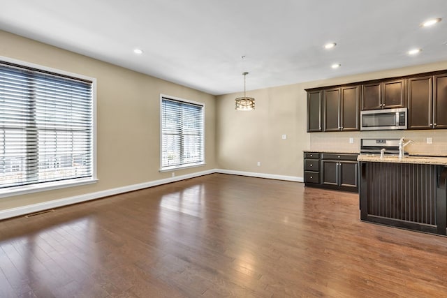 kitchen with range, tasteful backsplash, pendant lighting, dark brown cabinetry, and dark wood-type flooring