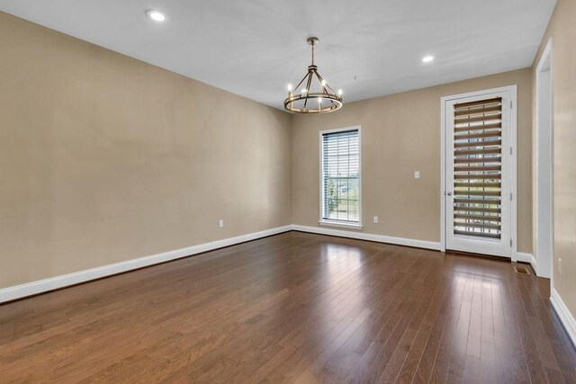 empty room featuring dark hardwood / wood-style flooring and an inviting chandelier