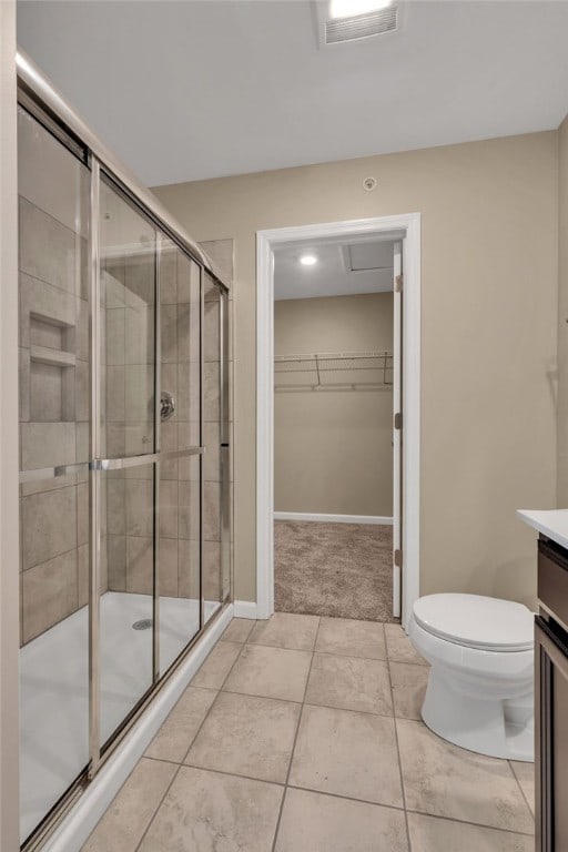 bathroom with vanity, walk in shower, toilet, and tile patterned floors