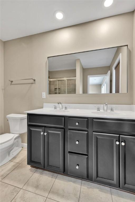 bathroom with toilet, tile patterned floors, and double sink vanity