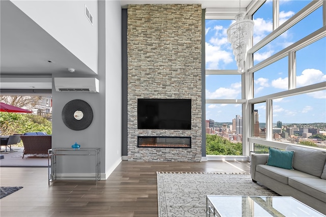 living room with a wall mounted air conditioner, dark hardwood / wood-style flooring, a stone fireplace, and plenty of natural light