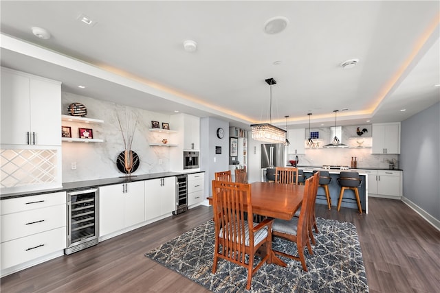 dining space with a tray ceiling, dark hardwood / wood-style flooring, and beverage cooler