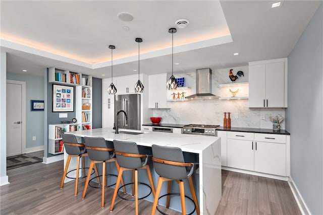 kitchen with wall chimney exhaust hood, sink, dark hardwood / wood-style floors, a center island with sink, and backsplash