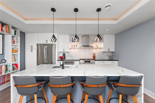 kitchen with a kitchen island with sink, wall chimney exhaust hood, sink, and stainless steel appliances