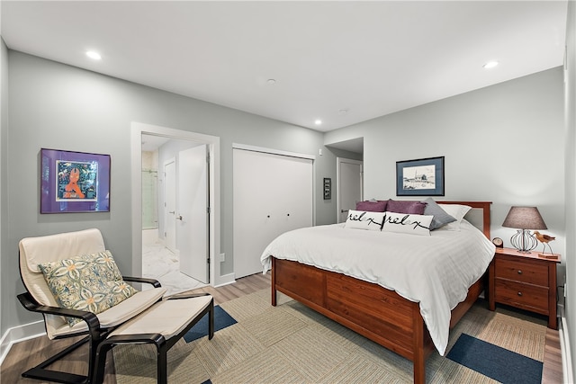 bedroom with ensuite bathroom, light hardwood / wood-style flooring, and a closet