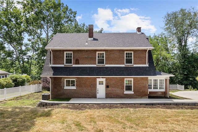 rear view of house with a patio, central AC unit, and a lawn