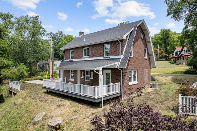 rear view of house featuring a wooden deck, a lawn, and cooling unit