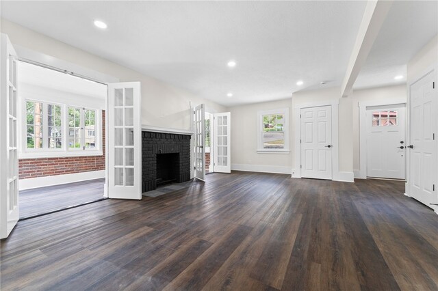 unfurnished living room featuring dark hardwood / wood-style flooring and a brick fireplace