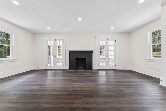 unfurnished living room with plenty of natural light, dark wood-type flooring, and french doors