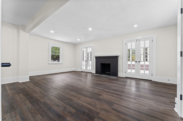 unfurnished living room featuring dark hardwood / wood-style floors, a fireplace, french doors, and a healthy amount of sunlight